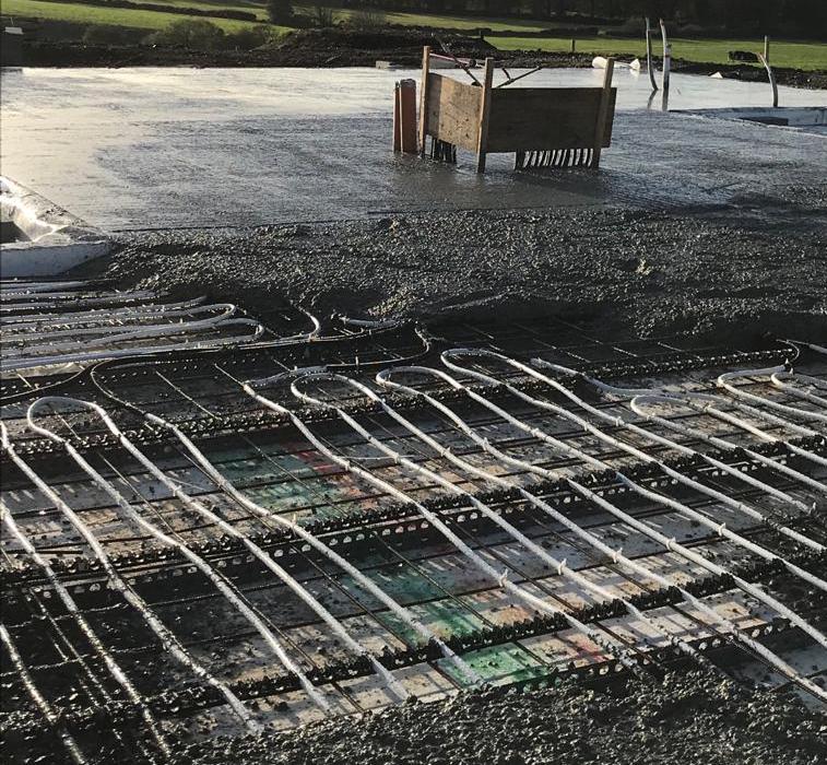 Concrete being poured on underfloor heating pipes and floor insulation